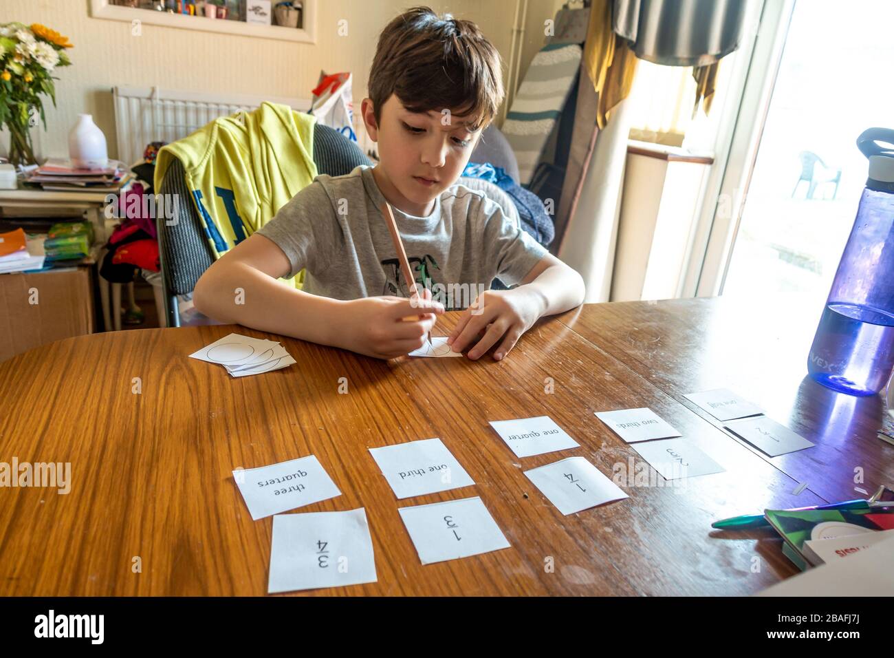 A boy is learning about fractions at home doing maths homework which has been sent during the coronavirus pandemic. Stock Photo