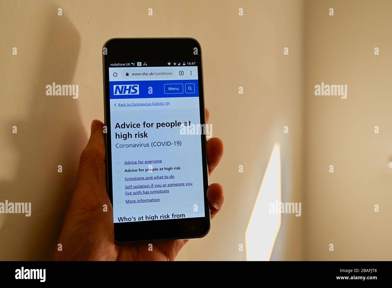 Mobile phone with NHS Coronavirus advice displayed on it's screen. Stock Photo