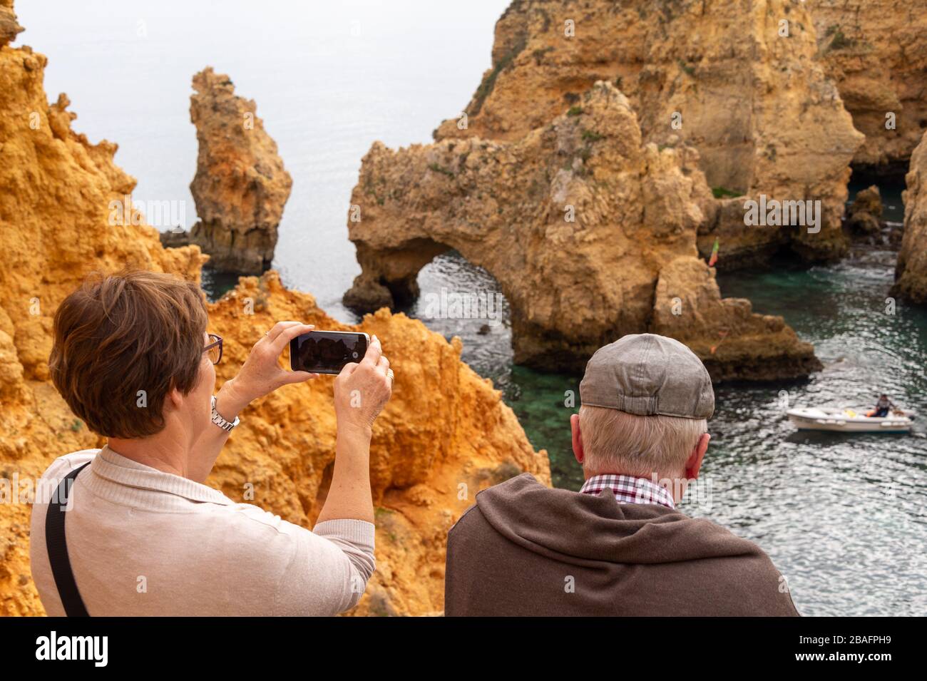 Lagos, Portugal - 4 March 2020: Tourist taking a picture of the cliffs at Ponta da Piedade Stock Photo