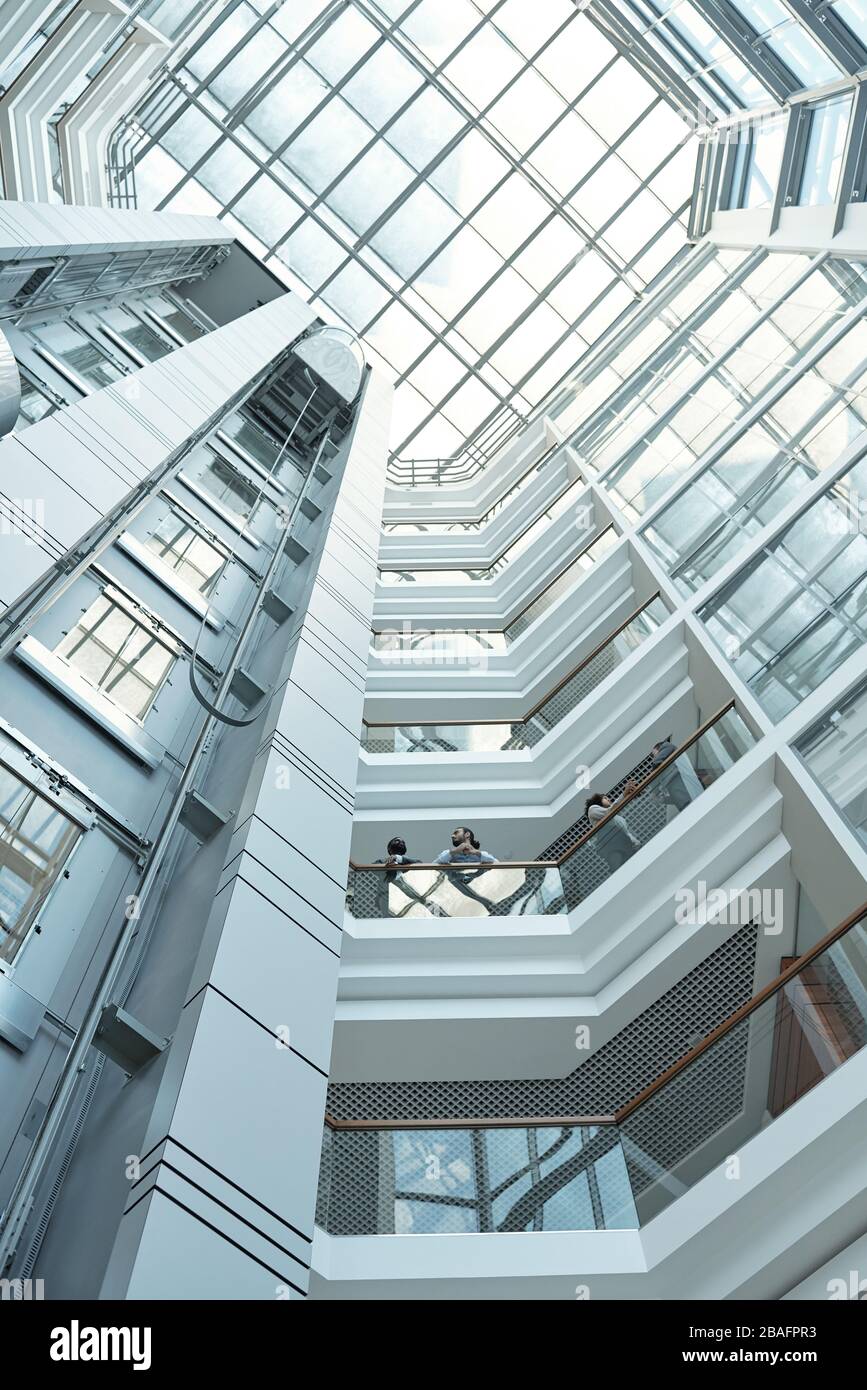 Below view of several business people discussing working points while standing on one of balconies inside large office center Stock Photo