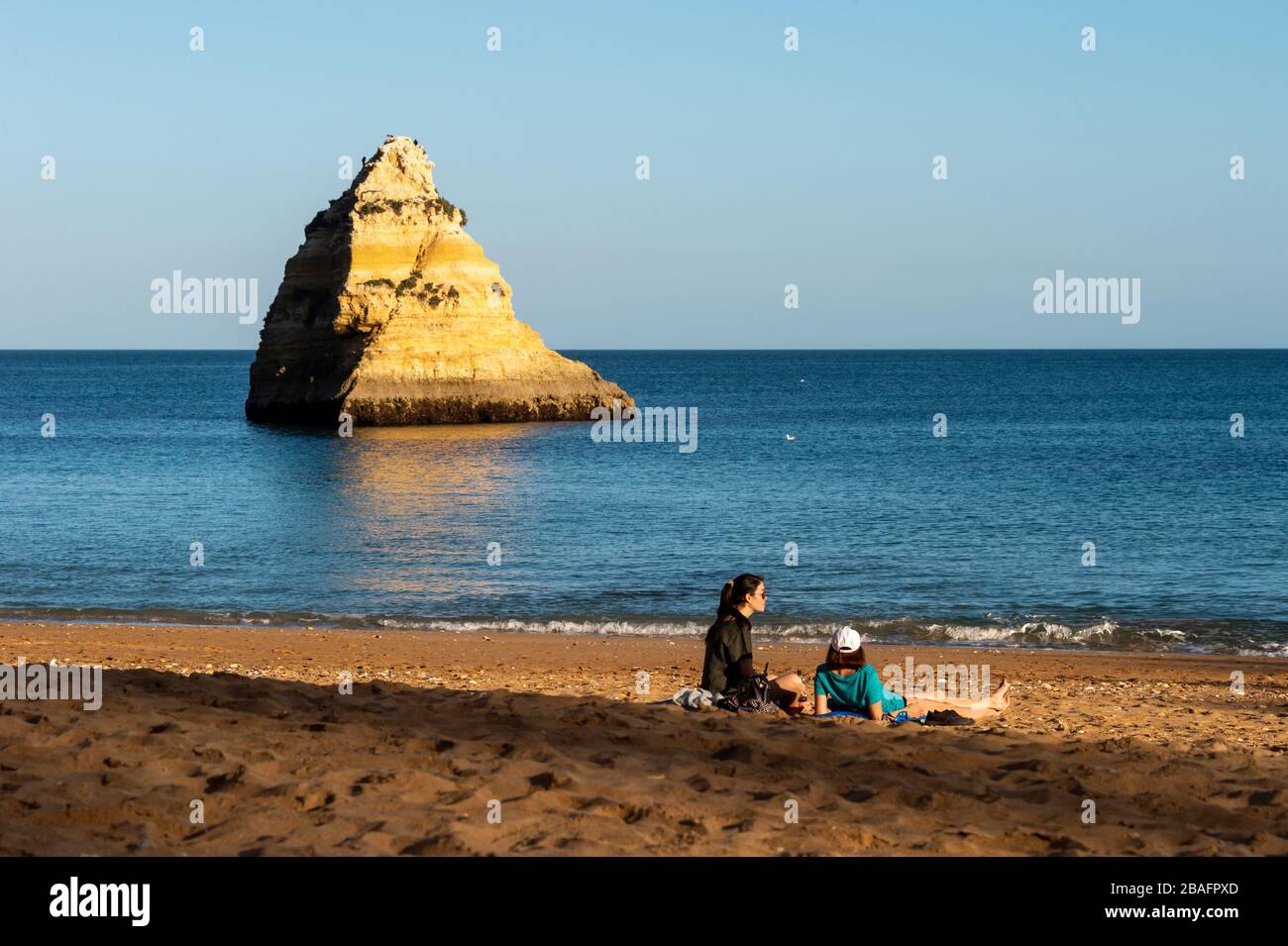 Lagos, Portugal - 4 March 2020: Two women sitting on sand at Dona Ana Beach Stock Photo