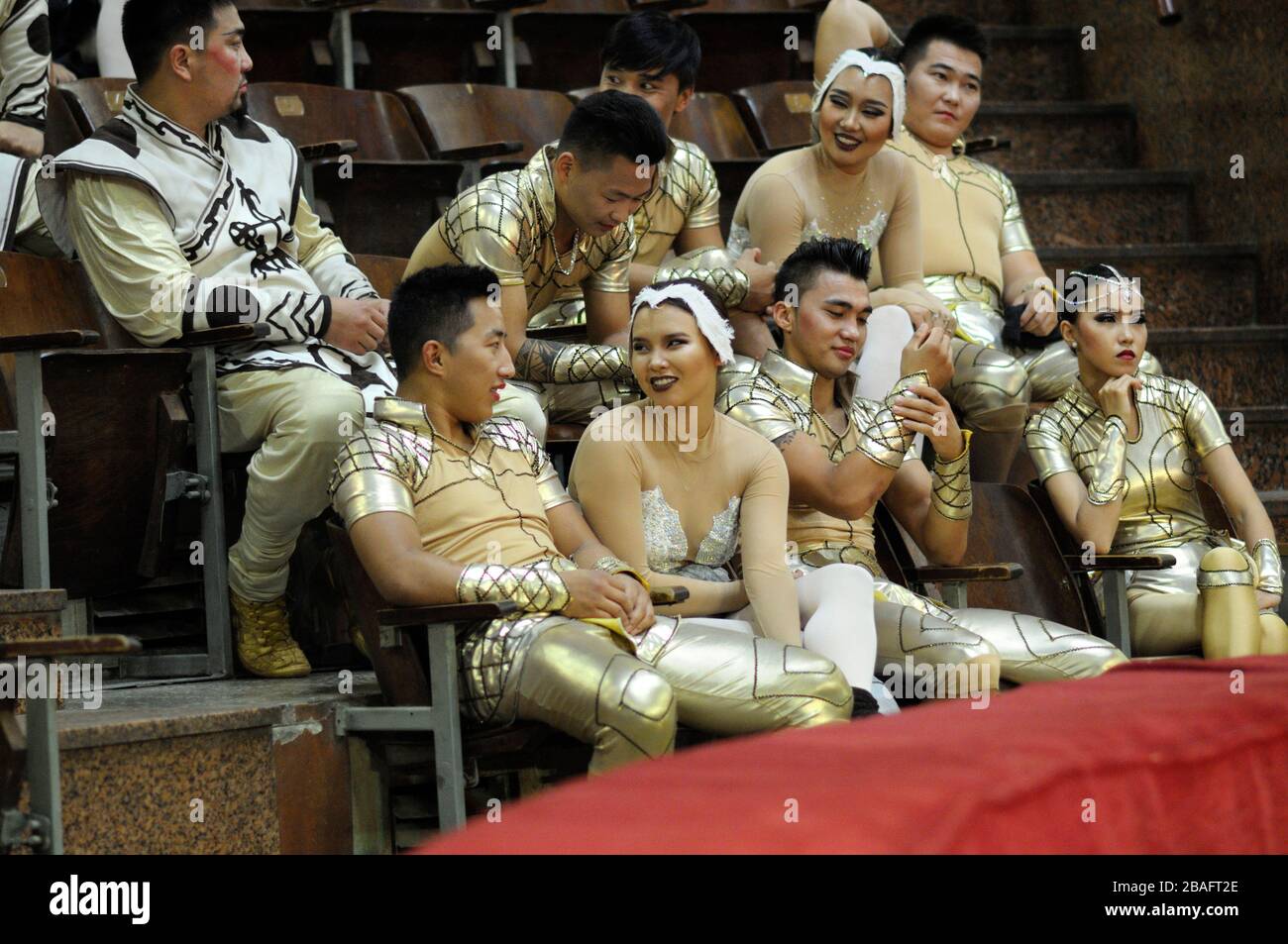 Group of Asian artists sitting on sits in front of arena of the National Kiev circus before giving press-conference. June 10, 2015. Kiev, Ukraine Stock Photo