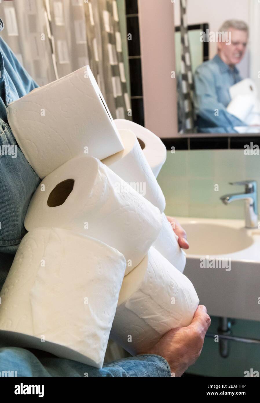 Senior man holding extra rolls of toilet paper during Coronavirus pandemic, USA  2020 Stock Photo