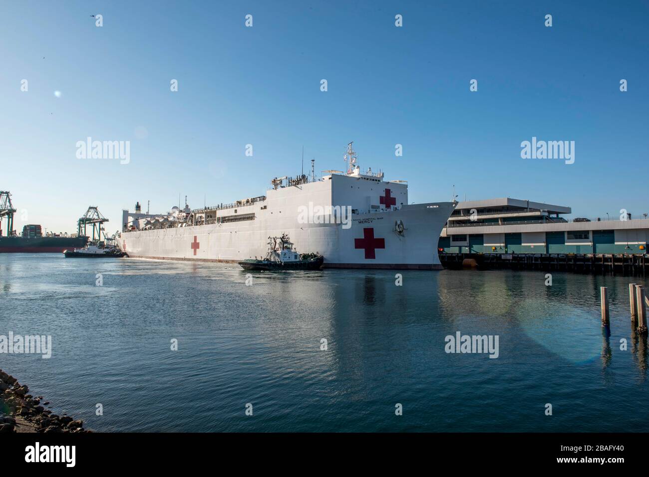 In this photo released by the United States Navy, the Military Sealift Command hospital ship USNS Mercy (T-AH 19) arrives in Los Angeles, California, March 27, 2020. Mercy deployed in support of the nation's COVID-19 response efforts, and will serve as a referral hospital for non-COVID-19 patients currently admitted to shore-based hospitals. This allows shore base hospitals to focus their efforts on COVID-19 cases. One of the Department of Defense's missions is Defense Support of Civil Authorities. DoD is supporting the Federal Emergency Management Agency, the lead federal agency, as well as s Stock Photo