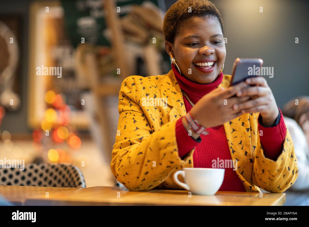 Happy young woman with smartphone in a cafe Stock Photo - Alamy