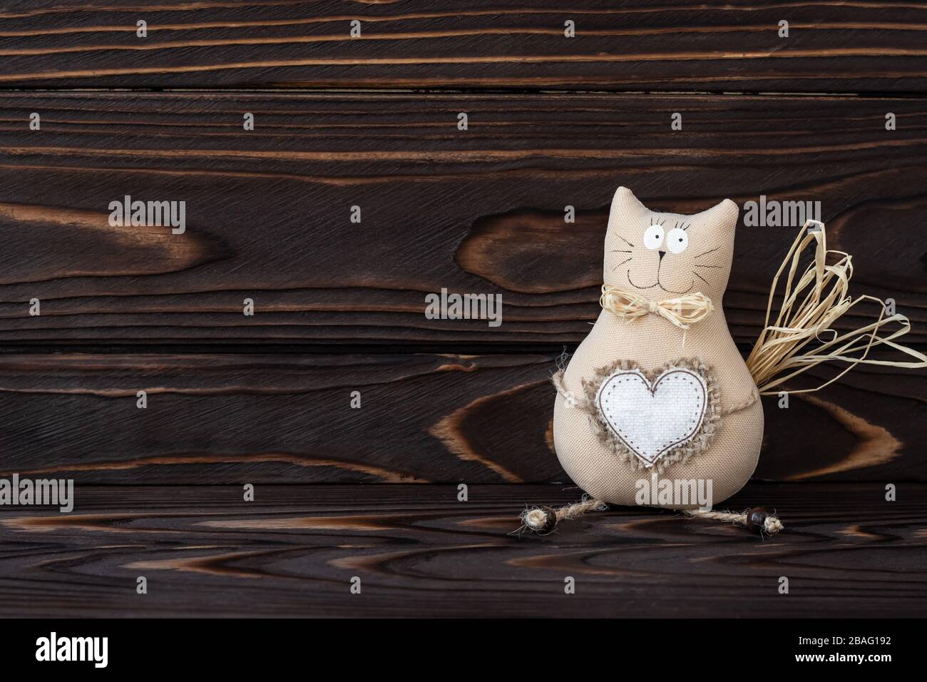 DIY, cat toy on wooden background. Hand made kitty with heart from textile. Dark wood natural boards, text space. Romantic card, love concept. Vintage Stock Photo