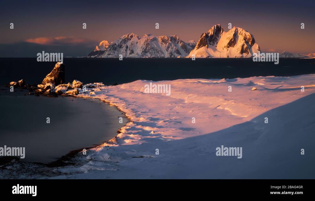 Tuusen Island in snow with Lofoten archipelago in background at sunset, Norway Stock Photo