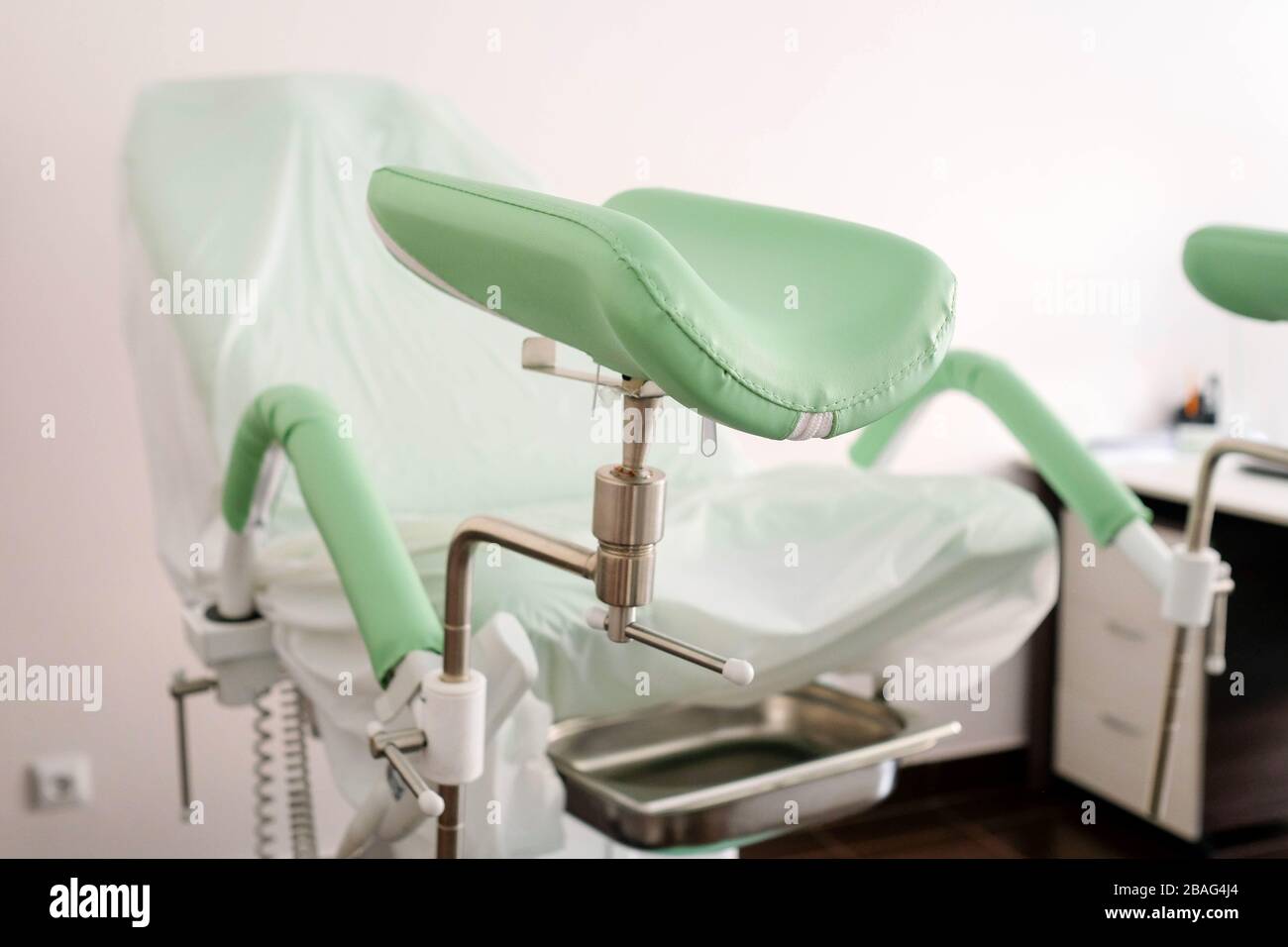 Gynecological chair with green footrests. Doctors office. Stock Photo