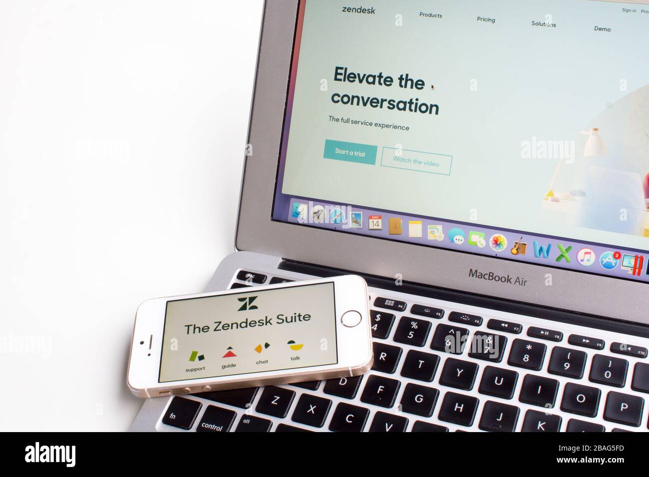 Zendesk Support Suite mobile app icons are seen on a smartphone with Zendesk webpage in the background. Stock Photo