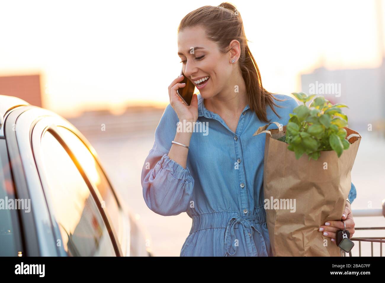 Young woman in car park, loading shopping into boot of car Stock Photo