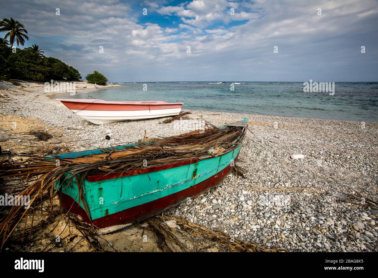 Dramatic seascape of aqua and red and white fishing boats on the caribbean coast, dominican republic Stock Photo