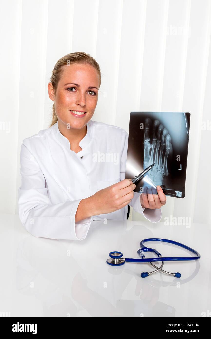 Eine junge Aerztin mit Stethoskop betrachtet ein Roentgenbild, MR: YES Stock Photo
