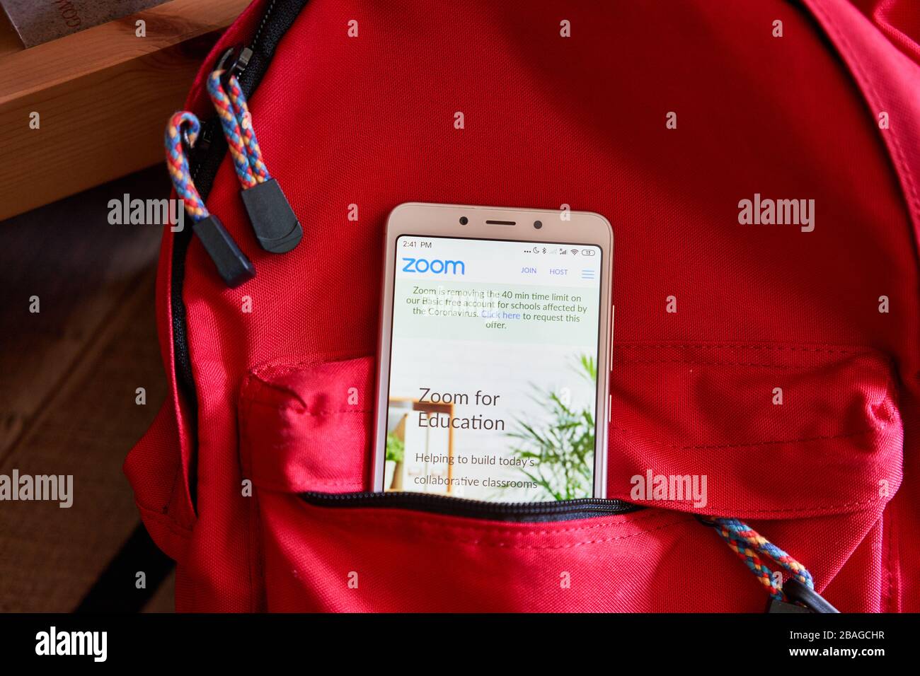Zoom Education Plan webpage seen on a phone in a school backpack. Zoom is giving k-12 schools its videoconferencing tools for free as schools close. Stock Photo