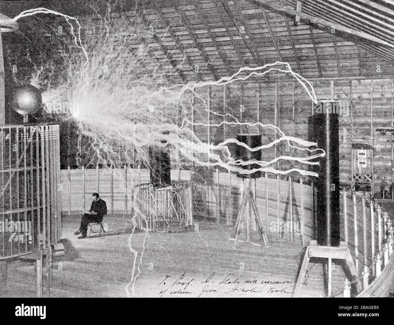 NIKOLA TESLA (1856-1943) Serbian-American inventor and electrical engineer in his laboratory in Colorado Springs about 1899. The image is a double exposure. Photographer Dickenson Alley first recorded the millions of volts created by Tesla's 'magnifying transmitter' then exposed the same plate with Tesla seated. Stock Photo