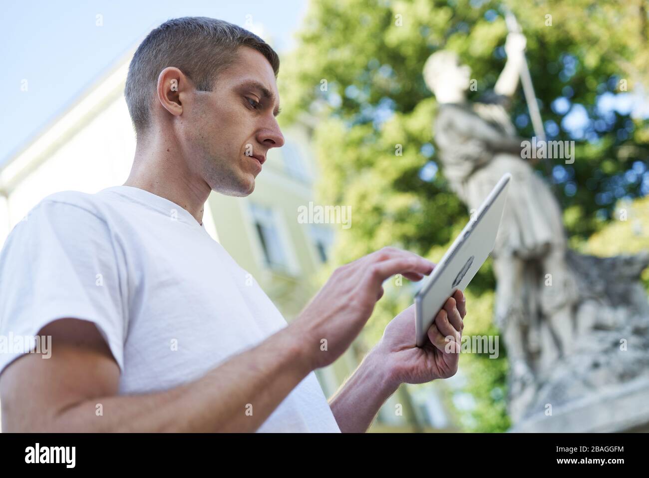 young handsome man standing in the street looking for something on his tablet Stock Photo