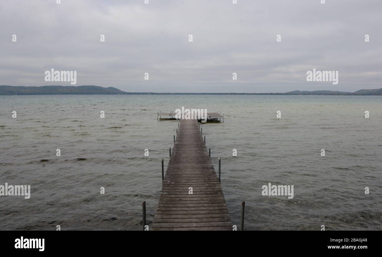 Long pier stretching out into the water under cloudy skies. Glen Lake