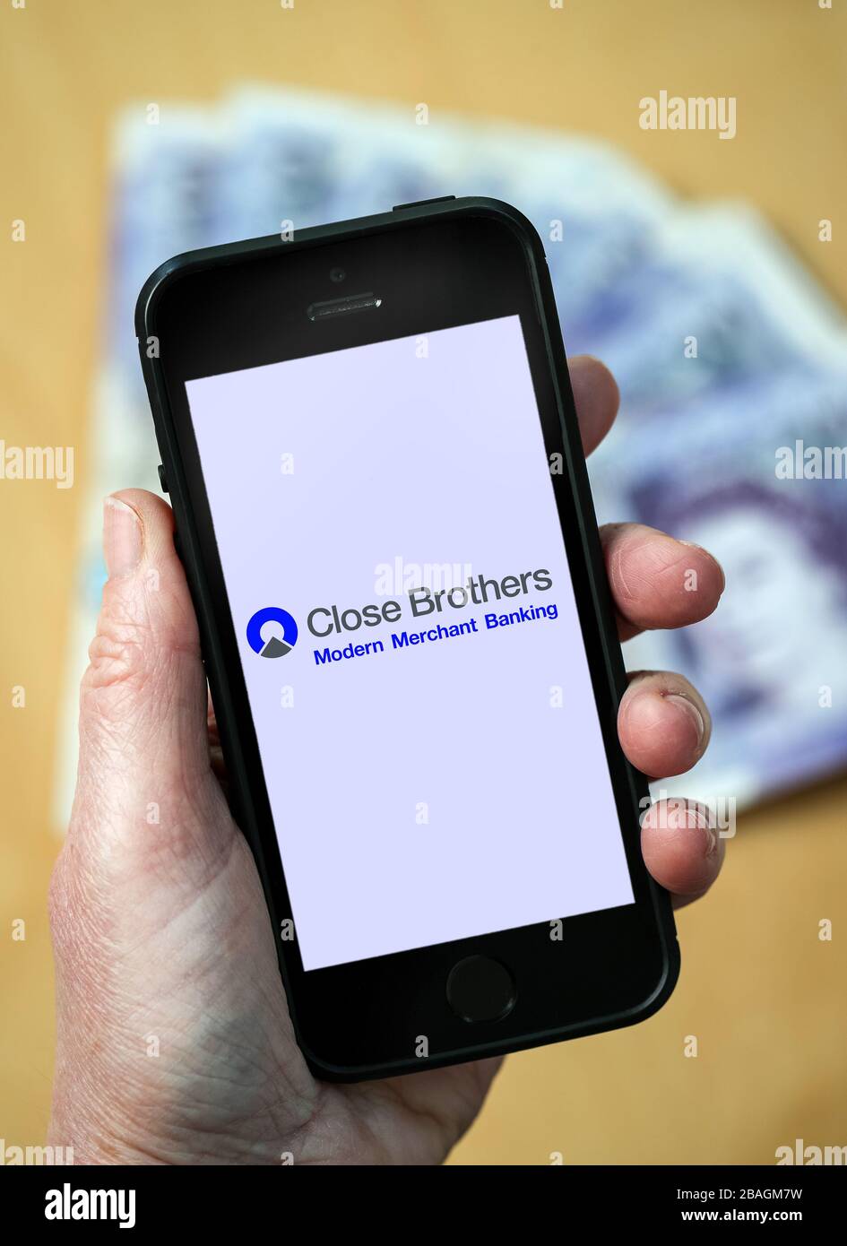 A woman looking at the Close Brothers Bank logo on a mobile phone. (editorial Use Only) Stock Photo