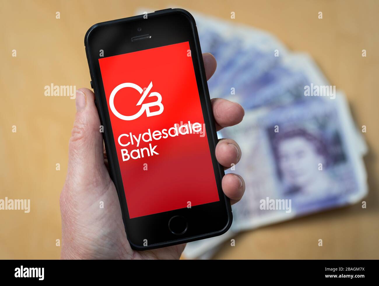 A woman looking at the Clydesdale Bank logo on a mobile phone. (editorial Use Only Stock Photo