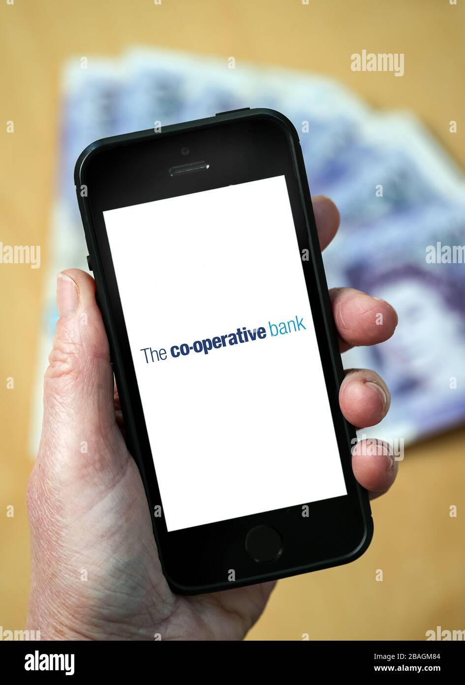 A woman looking at the The Co-operative Bank logo on a mobile phone. (editorial Use Only) Stock Photo