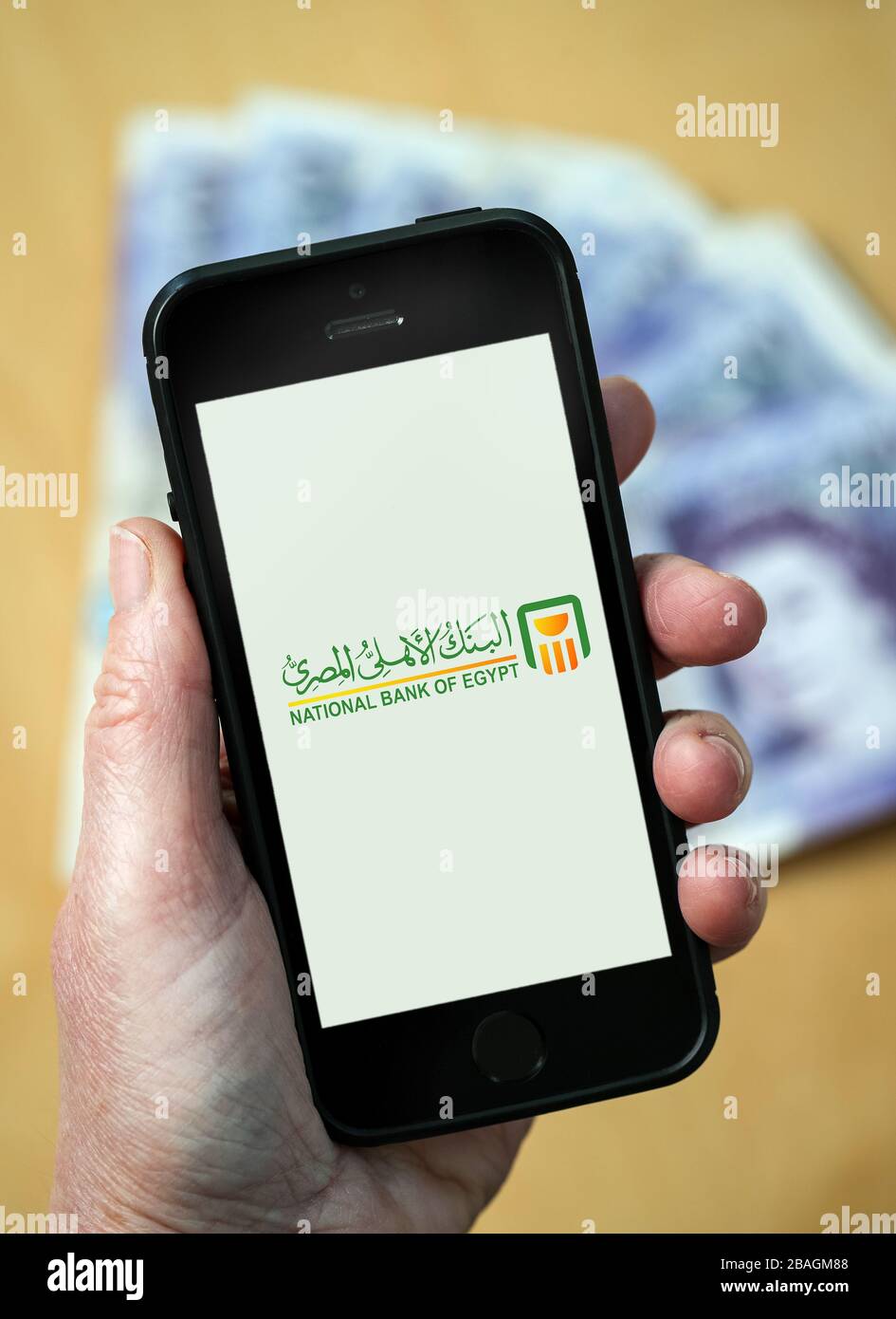 A woman looking at the National Bank of Egypt logo on a mobile phone. (editorial Use Only) Stock Photo