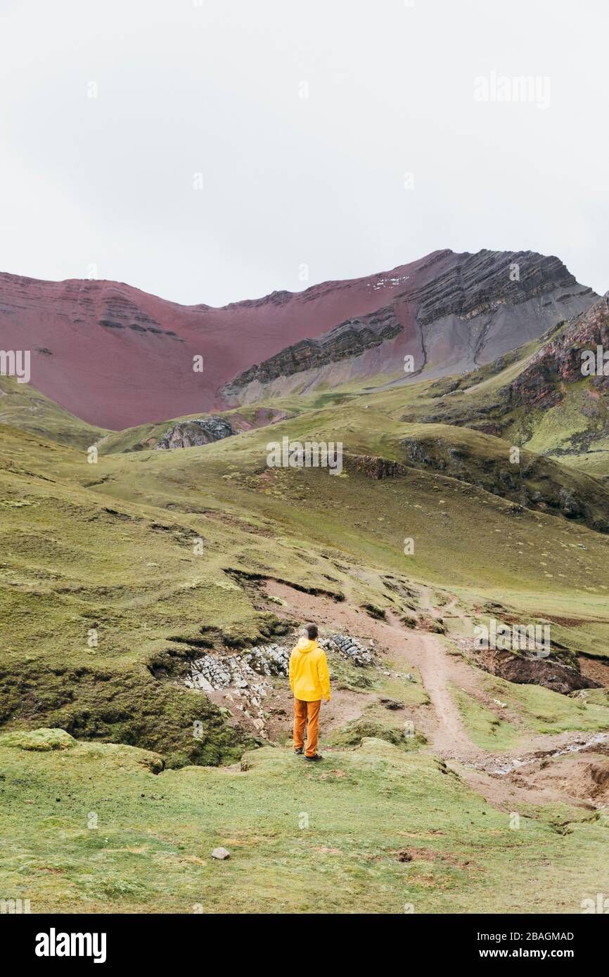 A man in a yellow jacket is standing on a hill in Peru Stock Photo
