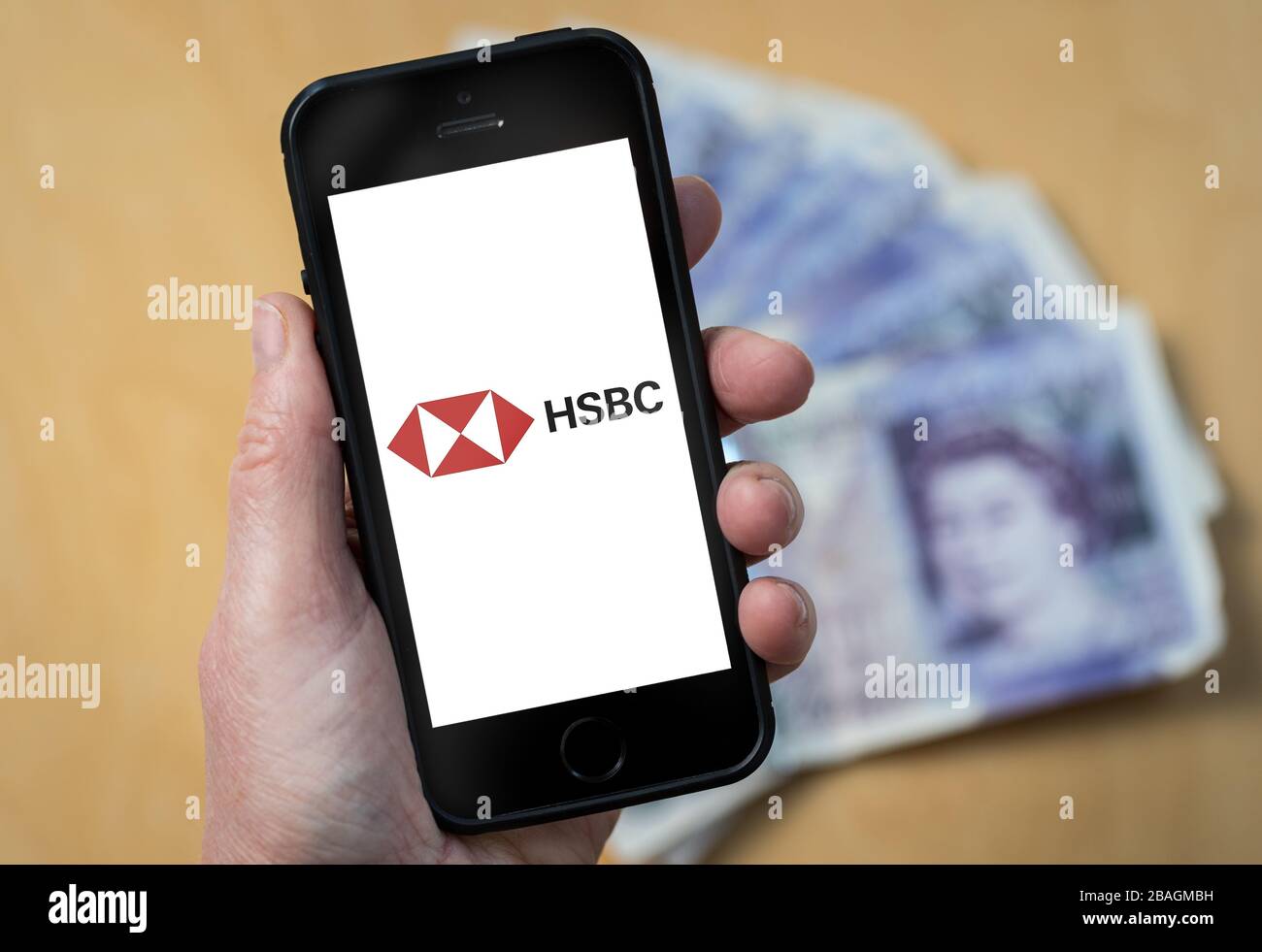 A woman looking at the HSBC Bank logo on a mobile phone. (editorial Use Only) Stock Photo