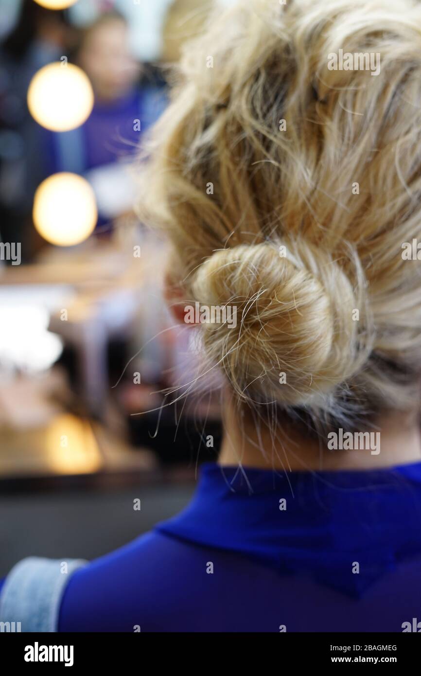 young woman with stray hairs and a messy bun hairstyle Stock Photo