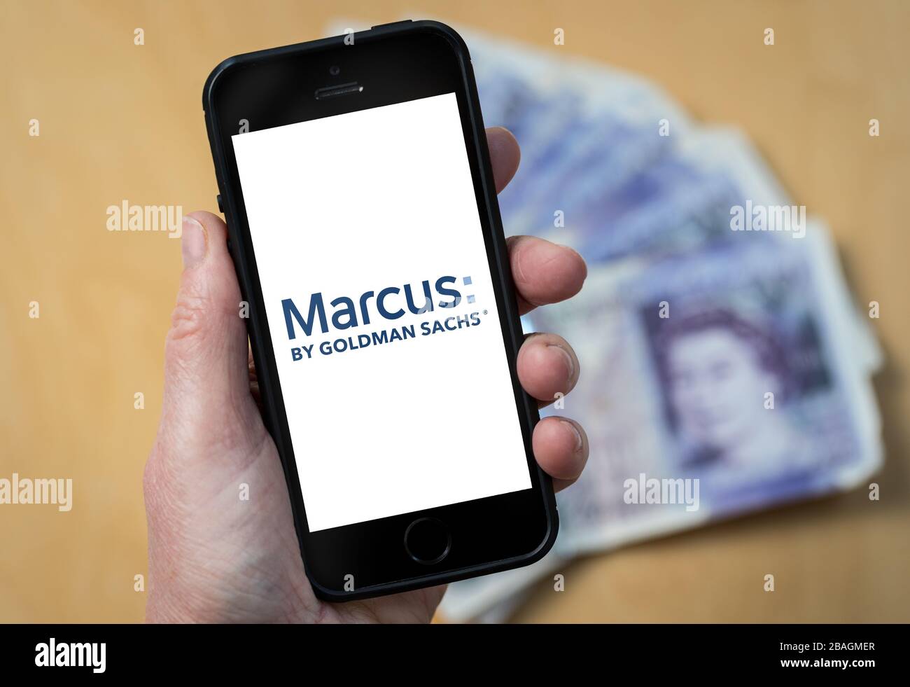 A woman looking at the Marcus Bank by Goldman Sachs logo on a mobile phone. (editorial Use Only) Stock Photo