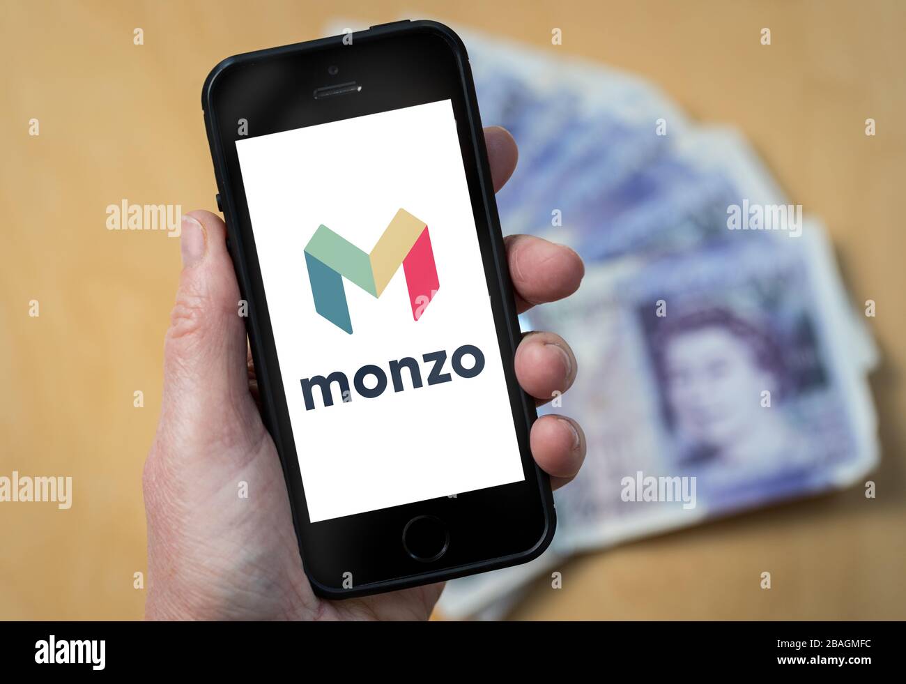 A woman looking at the Monzo Bank logo on a mobile phone. (editorial Use Only) Stock Photo