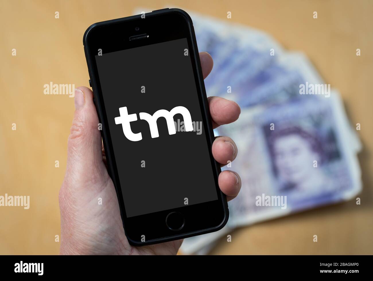 A woman looking at the Think Money Bank logo on a mobile phone. (editorial Use Only) Stock Photo