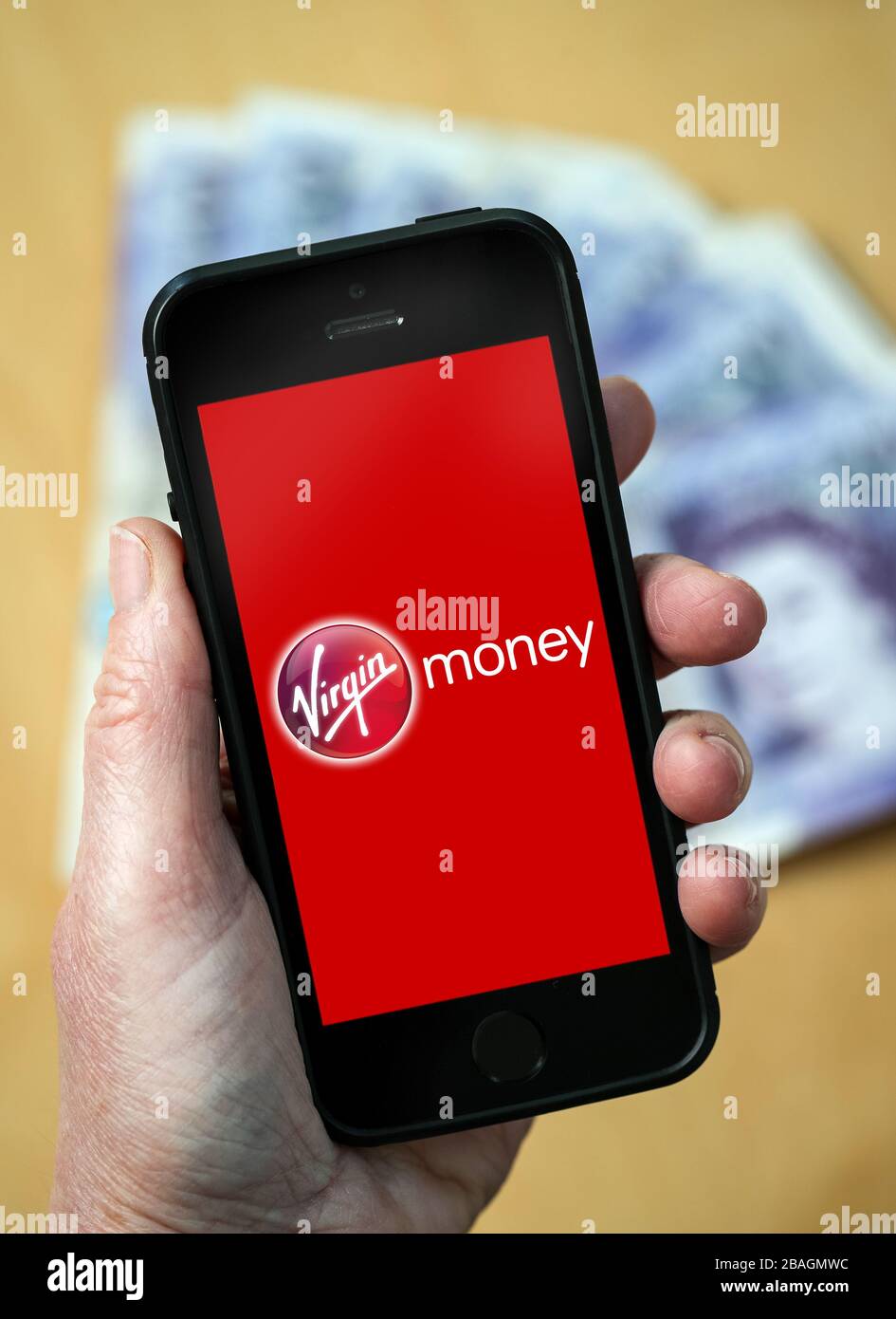 A woman looking at the Virgin Money logo on a mobile phone. (editorial Use Only) Stock Photo