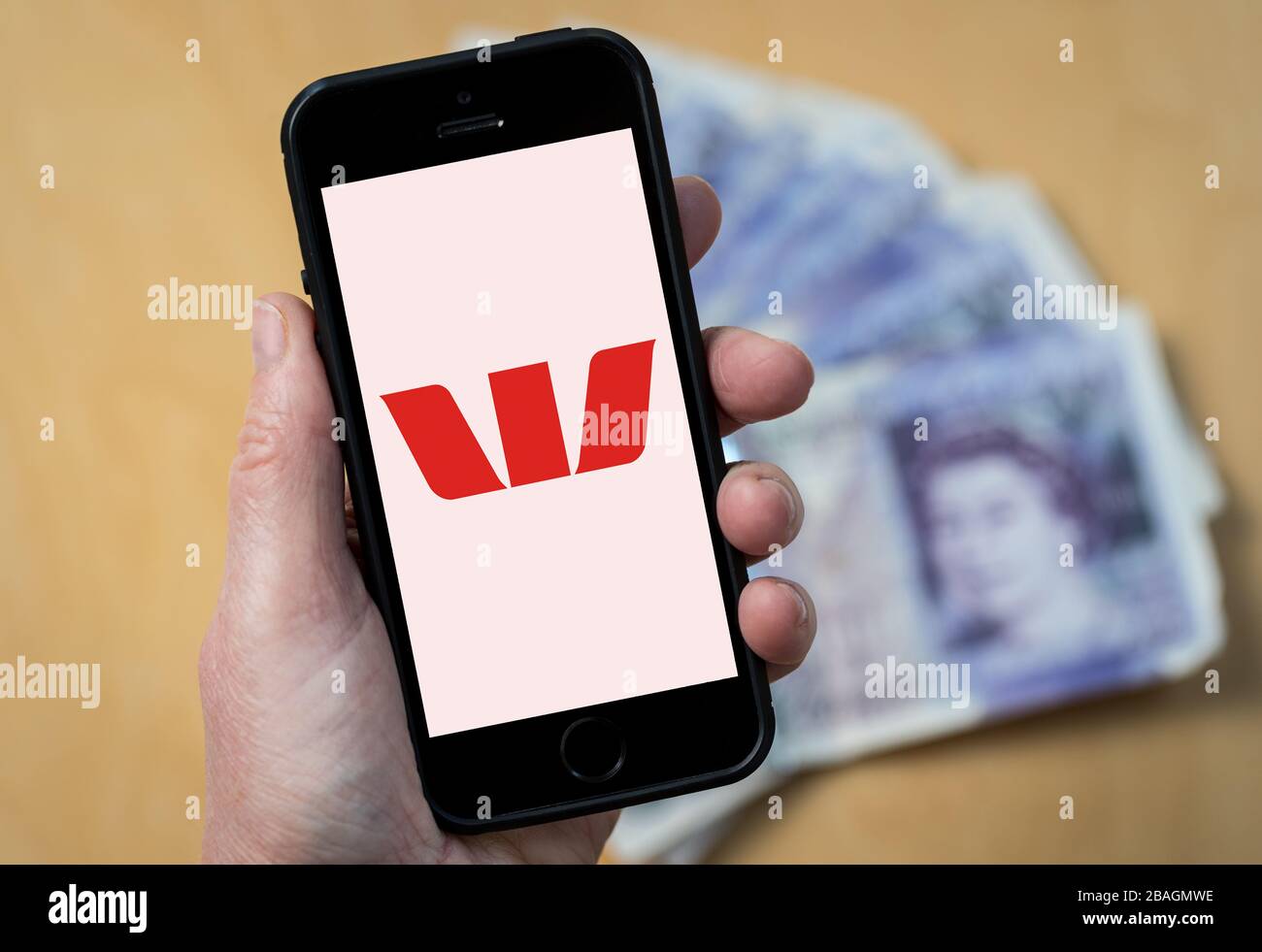 A woman looking at the Westpac Bank logo on a mobile phone. (editorial Use Only) Stock Photo