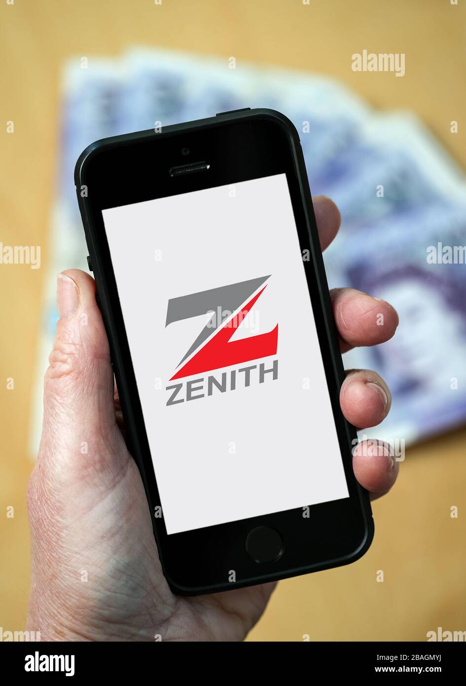 A woman looking at the Zenith Bank logo on a mobile phone. (editorial Use Only) Stock Photo