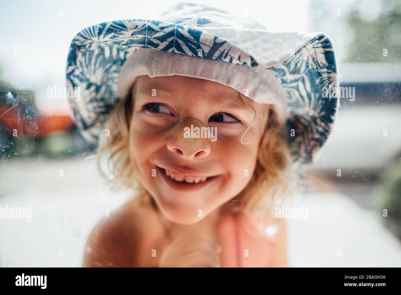 Little boy with smooshed face in window wearing bucket hat Stock Photo
