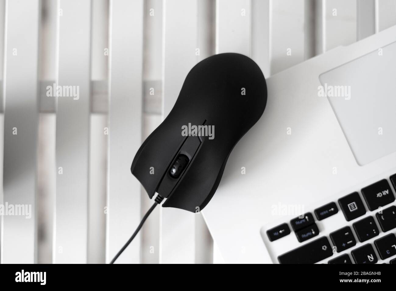 Black mouse on top of a white laptop. Black mouse concept. Stock Photo