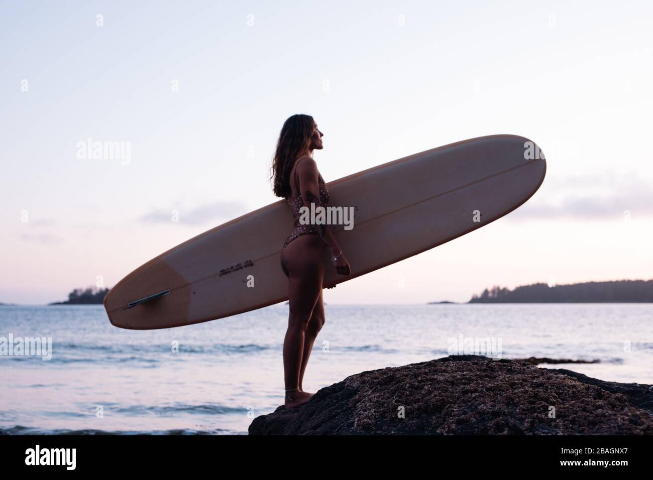 Beautiful, fit woman with surfboard on beach in Tofino Stock Photo