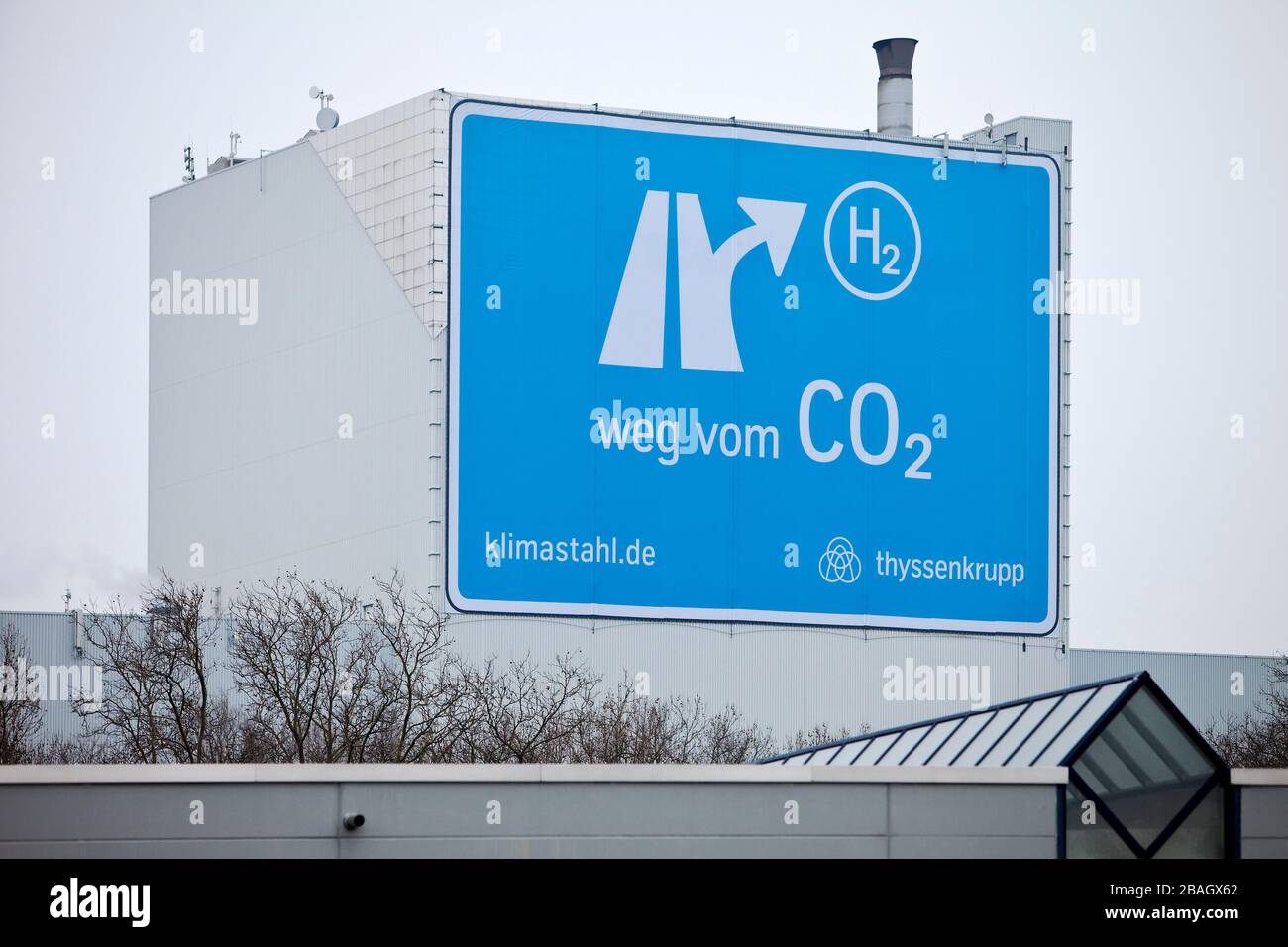 large-format poster near the motorway A 40, from CO2 to H2, Klimastahl, factory hall of ThyssenKrupp Steel Europe, Germany, North Rhine-Westphalia, Ruhr Area, Bochum Stock Photo