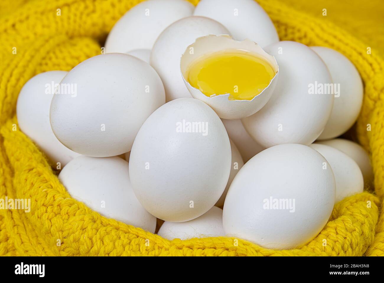 white chicken eggs in yellow wool sweater. lot of white eggs close up. broken chicken white egg. Stock Photo