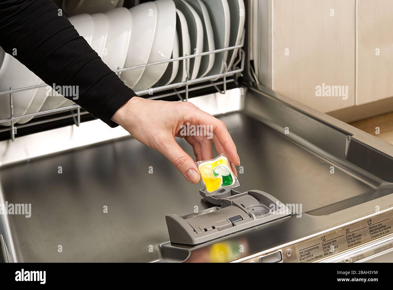 Putting tab into full integrated dishwasher close up. dishwasher