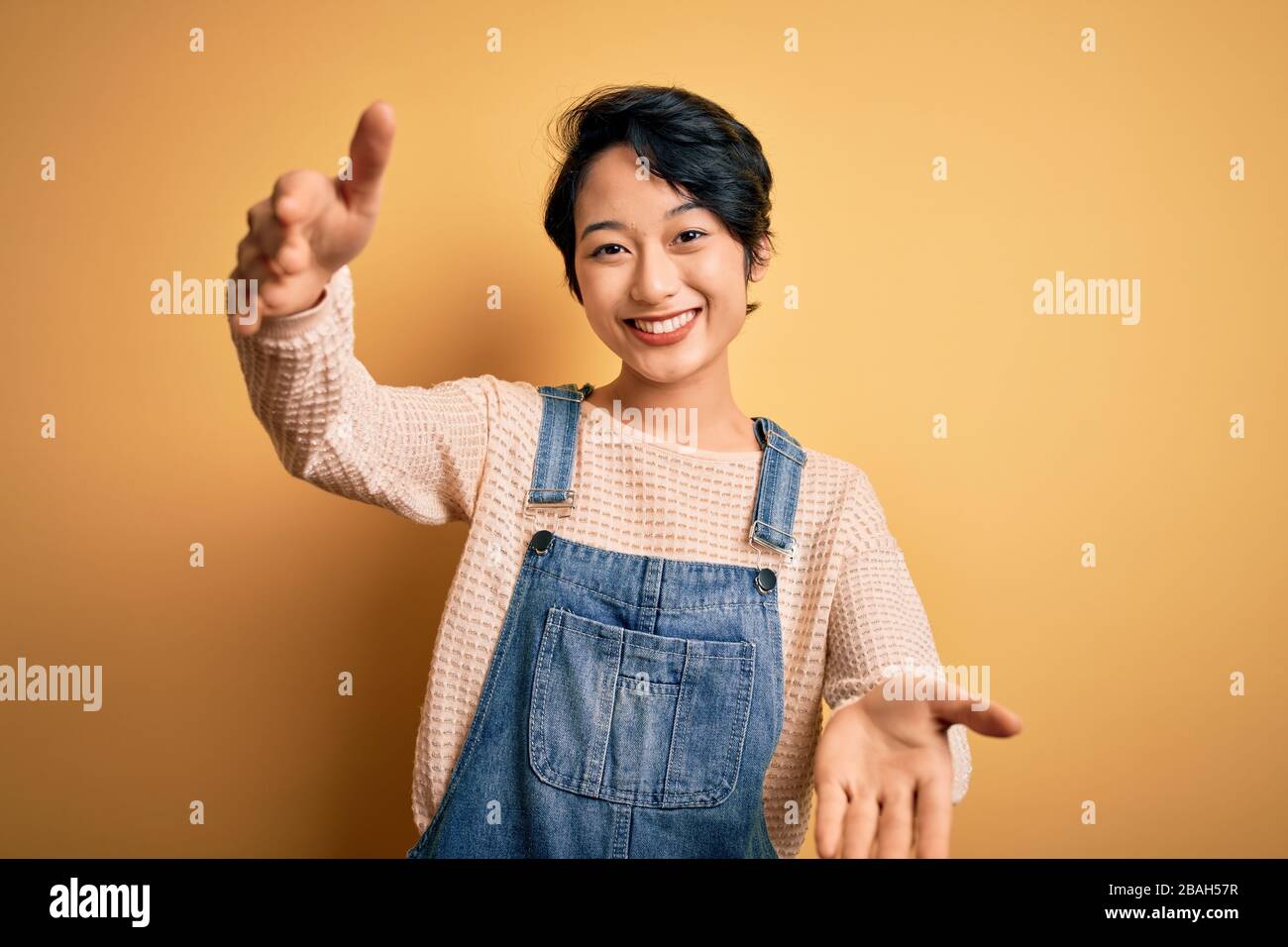 Young beautiful asian girl wearing casual denim overalls over isolated ...