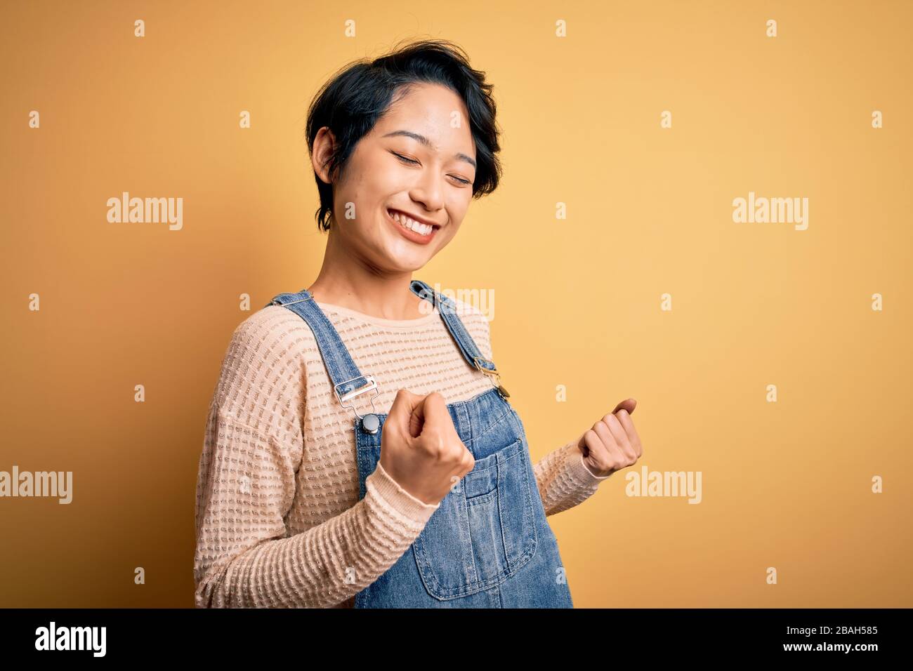 Young beautiful asian girl wearing casual denim overalls over isolated ...