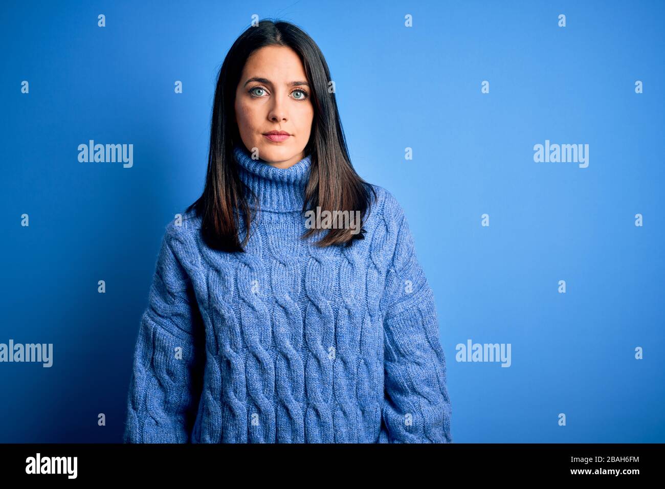 Young brunette woman with blue eyes wearing casual turtleneck sweater ...