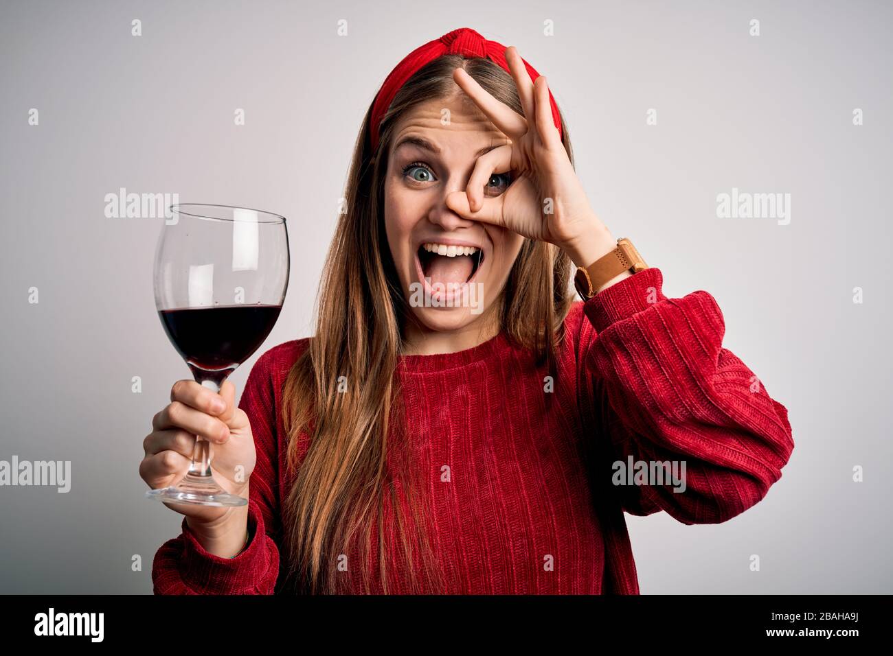Young beautiful redhead woman drinking glass of red wine over isolated ...