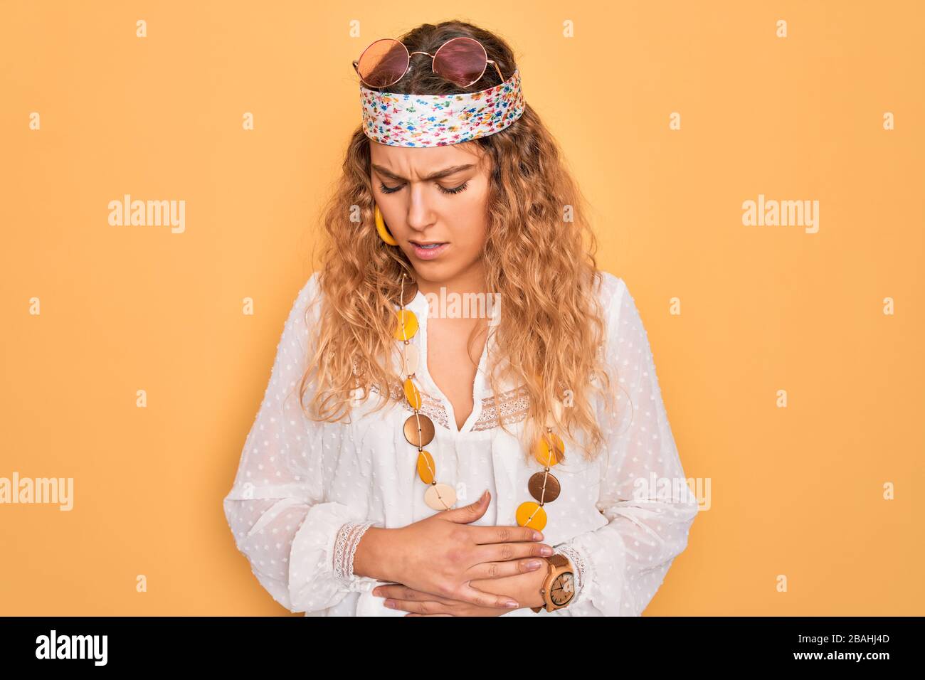 Young beautiful blonde hippie woman with blue eyes wearing sunglasses and accessories with hand on stomach because indigestion, painful illness feelin Stock Photo