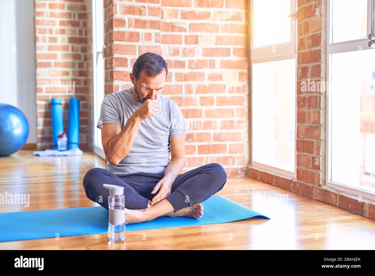Middle age handsome sportman sitting on mat doing stretching yoga Middle age handsome sportman sitting on mat doing stretching yoga