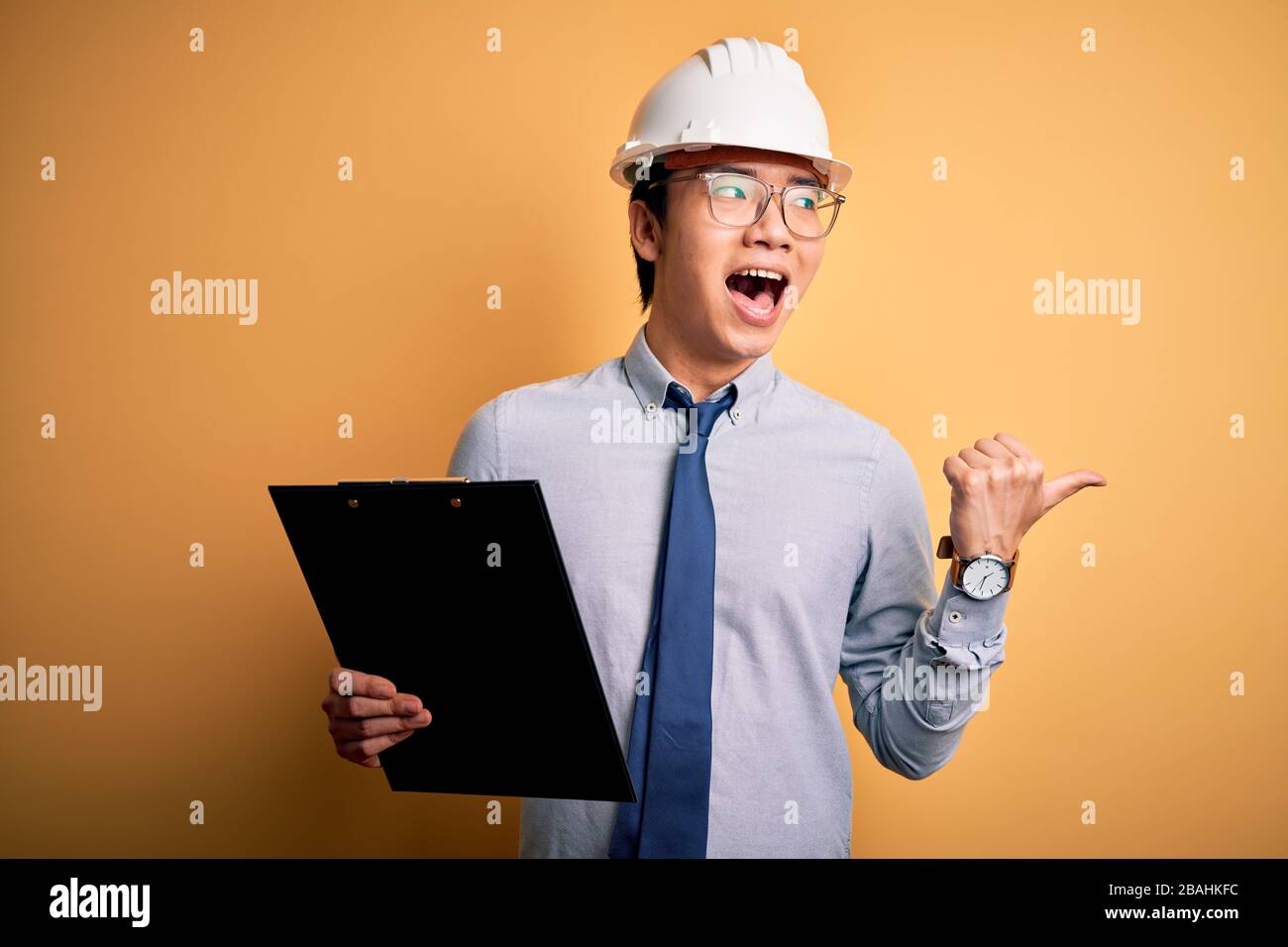 Young handsome chinese engineer man wearing safety helmet holding ...