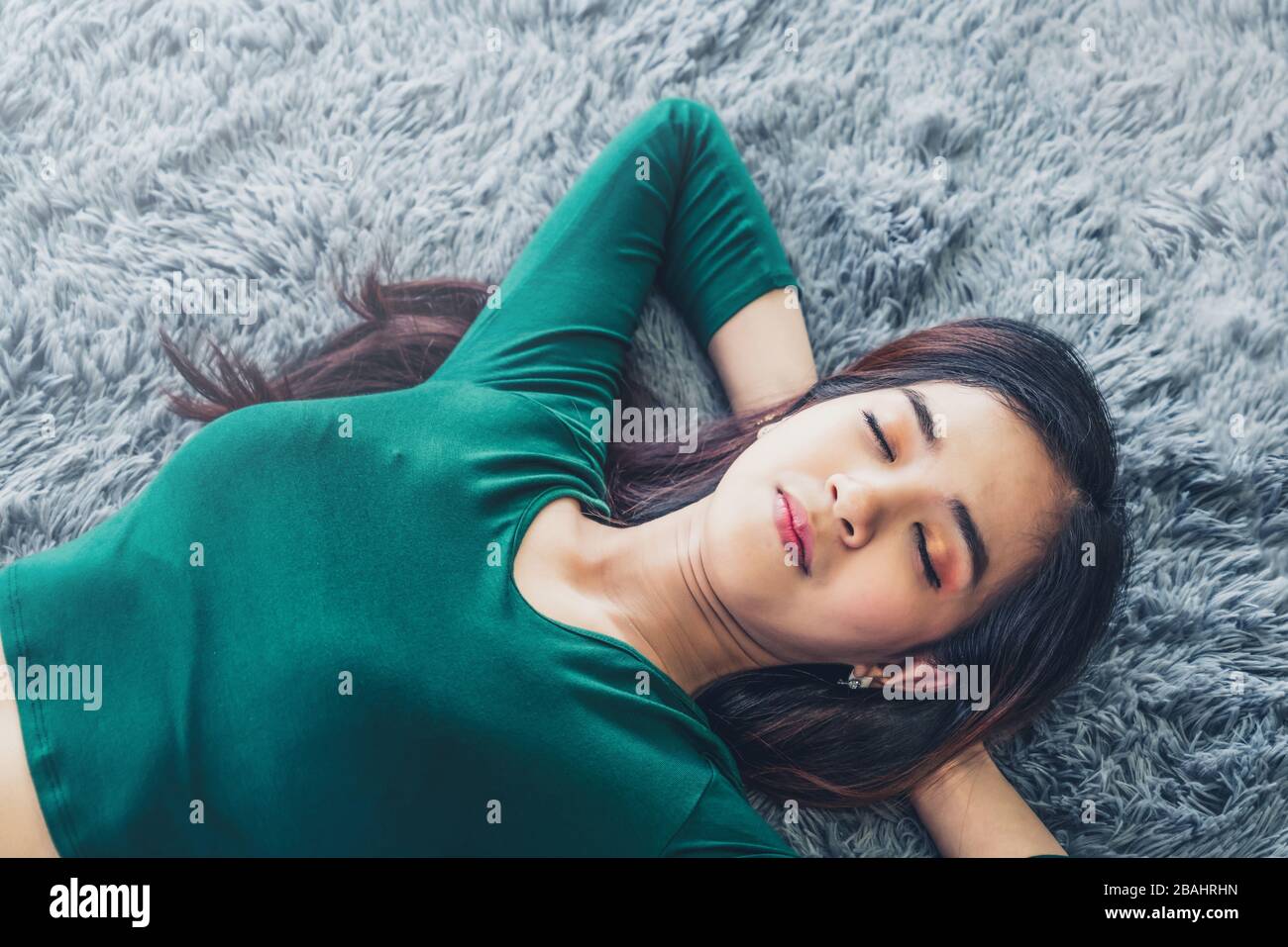 Happy Asian couple lying together on carpet at living room floor. Love relationship and lifestyle concept. Stock Photo