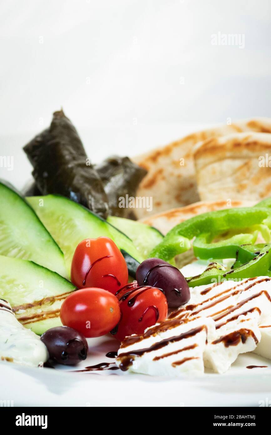 Simple Greek meze food platter; with vegetables, pita, grape leaves, feta and balsamic glaze Stock Photo