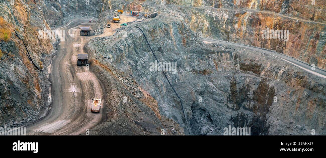 In the gold mine,  a large yellow truck carrying gold ore to the processing machine, panorama view Stock Photo