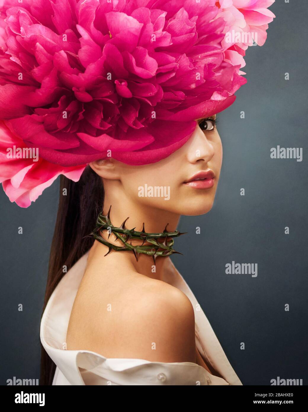 Surreal portrait of a girl with peonies flowers on head and rose thorns on the neck. In Ful Bloom. Interior photo art in art deco style. Beautiful Stock Photo
